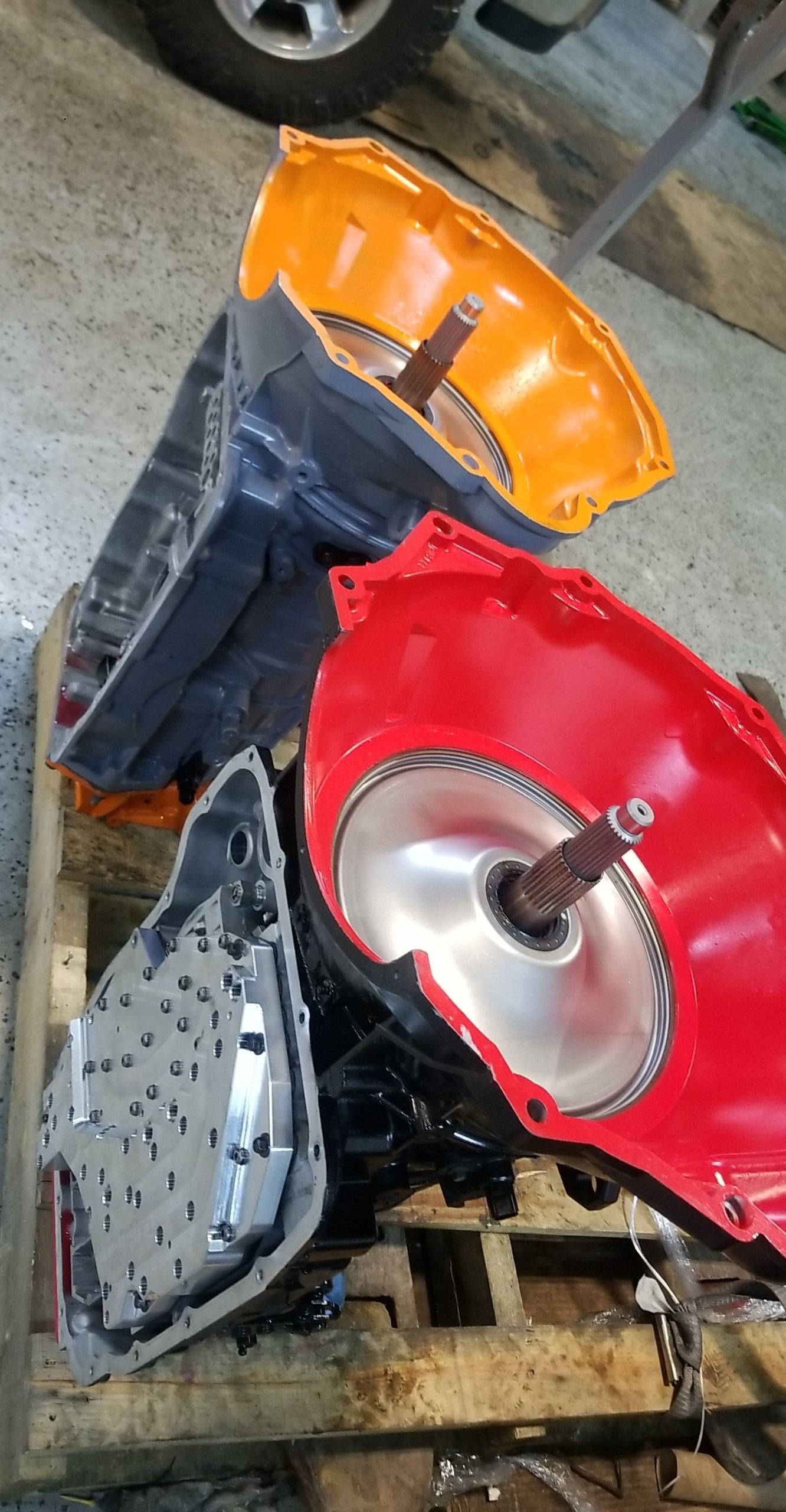 A red and black engine is sitting on top of a wooden pallet.