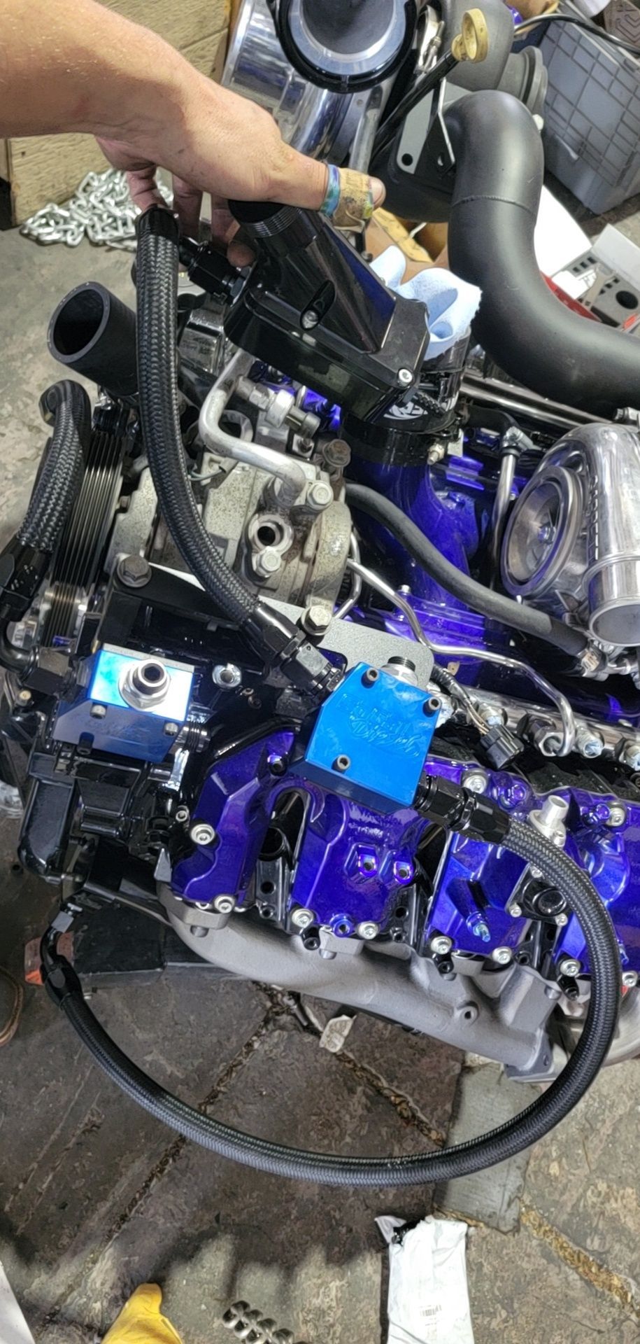 A person is working on a purple engine in a garage.