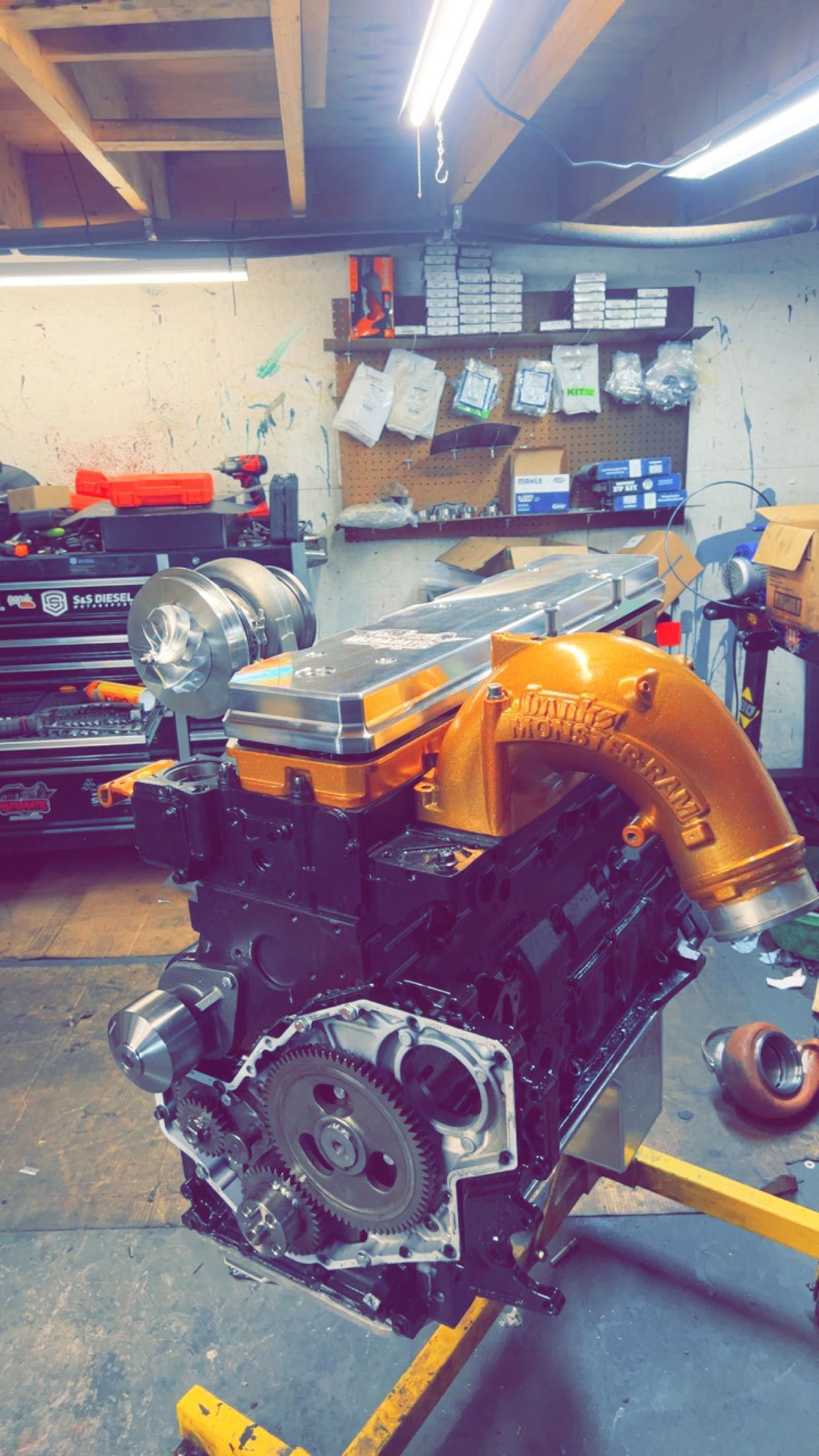 A large engine is sitting on top of a yellow lift in a garage.