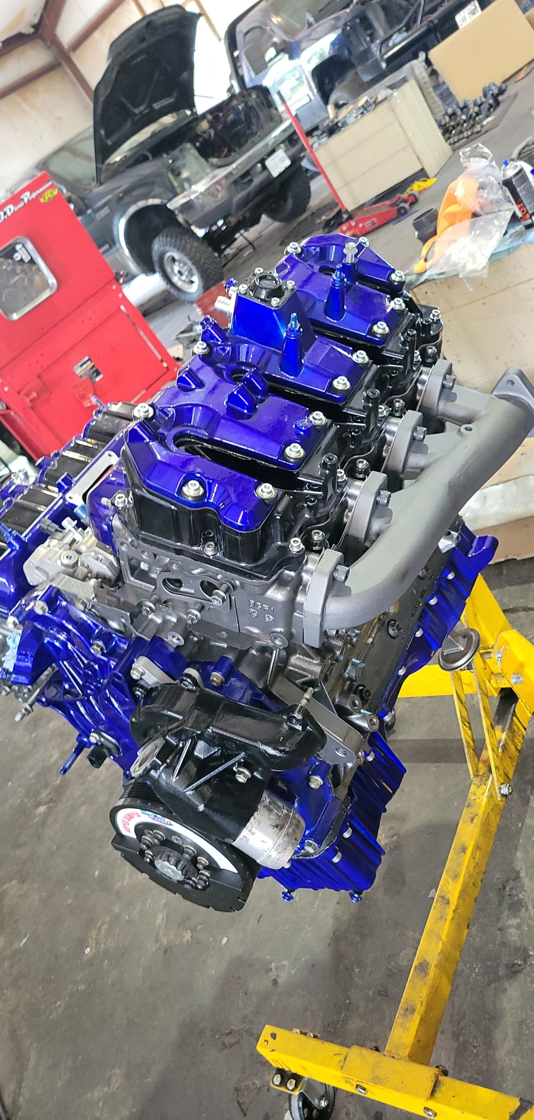 A blue and black engine is sitting on top of a yellow stand in a garage.
