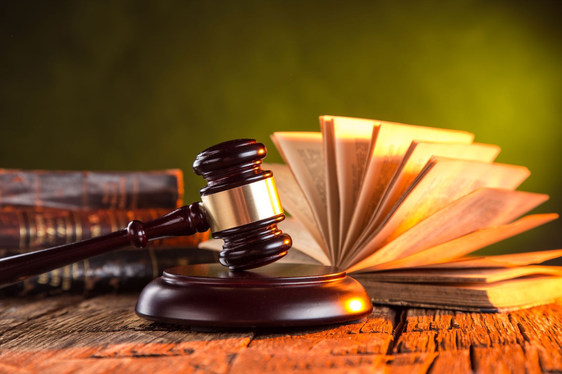 Judge’s gavel beside an open law book on a wooden desk, warm golden lighting.