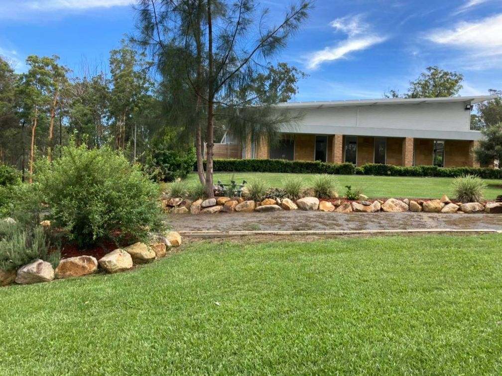 A Large House With A Lot Of Grass And Rocks In Front Of It — United Funeral Care In Kempsey, NSW