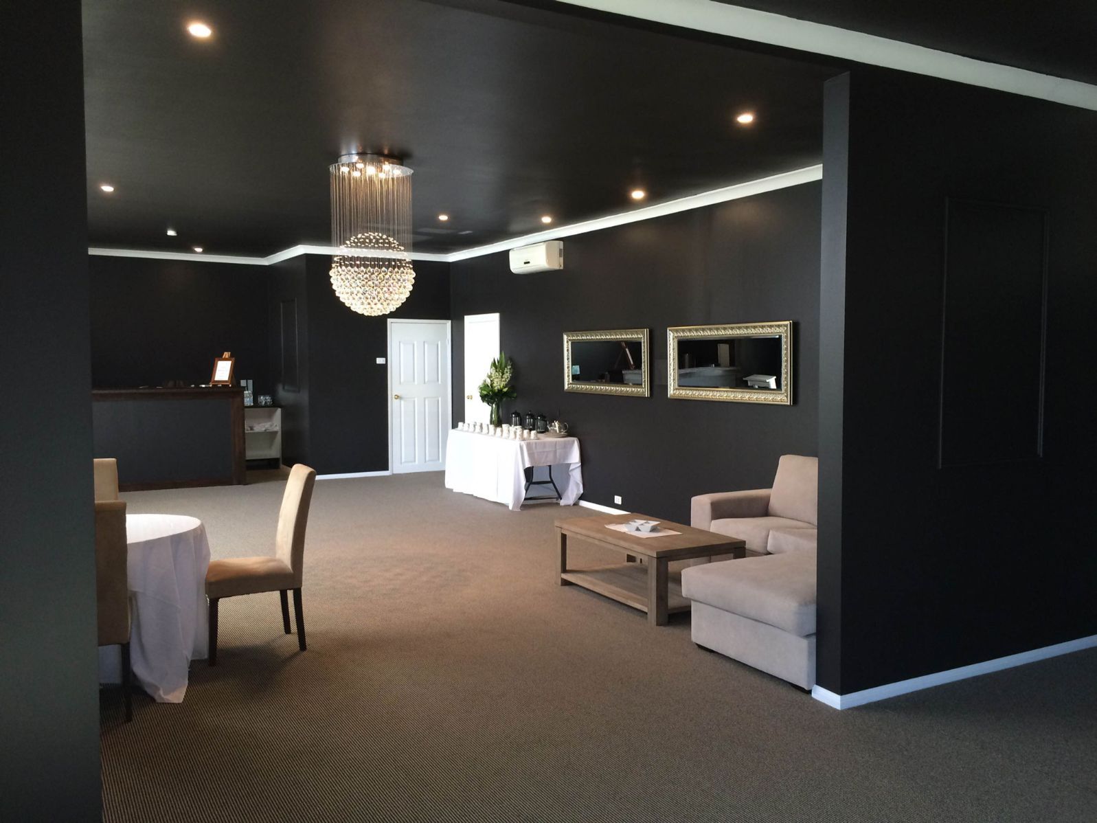 A Large Room With Black Walls And A Chandelier Hanging From The Ceiling — United Funeral Care In Kempsey, NSW