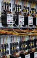 Rows of electrical relays and wiring in a control panel, with many colored cables and labeled components