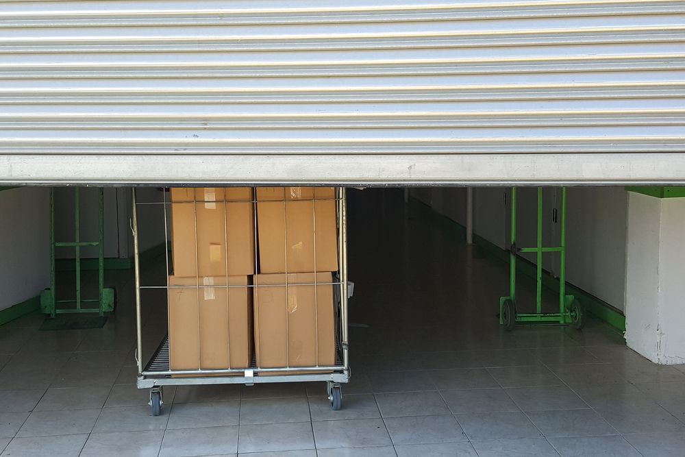 A Cart Filled With Cardboard Boxes Is Sitting Under The Storage Door — Howlett's Mini Storage In Bundaberg East, QLD