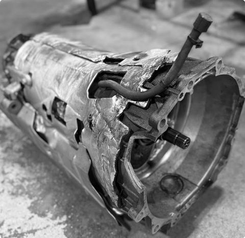 Damaged metal transmission housing with a torn outer casing and exposed internal parts on a workshop floor | G3 Transmission and Auto