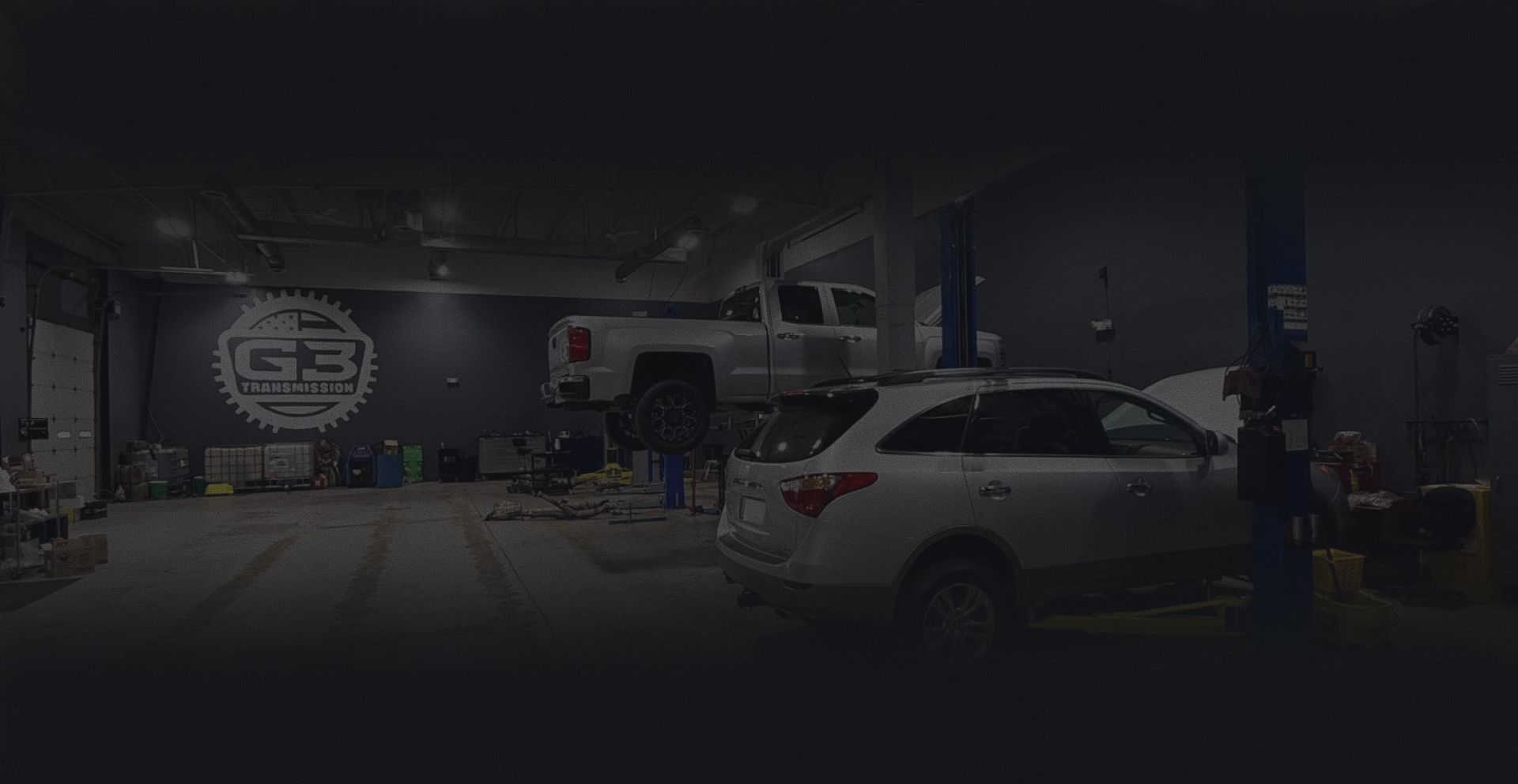 Car repair shop interior with a white SUV on the right and tools and equipment across the garage. | G3 Transmission and Auto