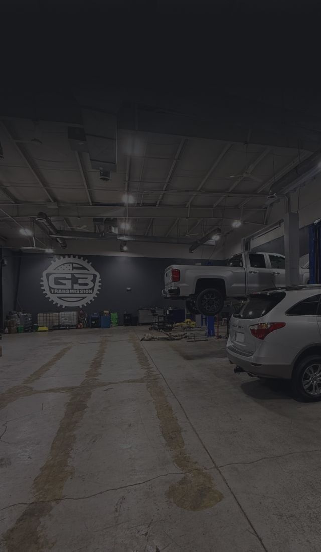 Parking garage with a white SUV on the right and a large wall logo in the background. | G3 Transmission and Auto