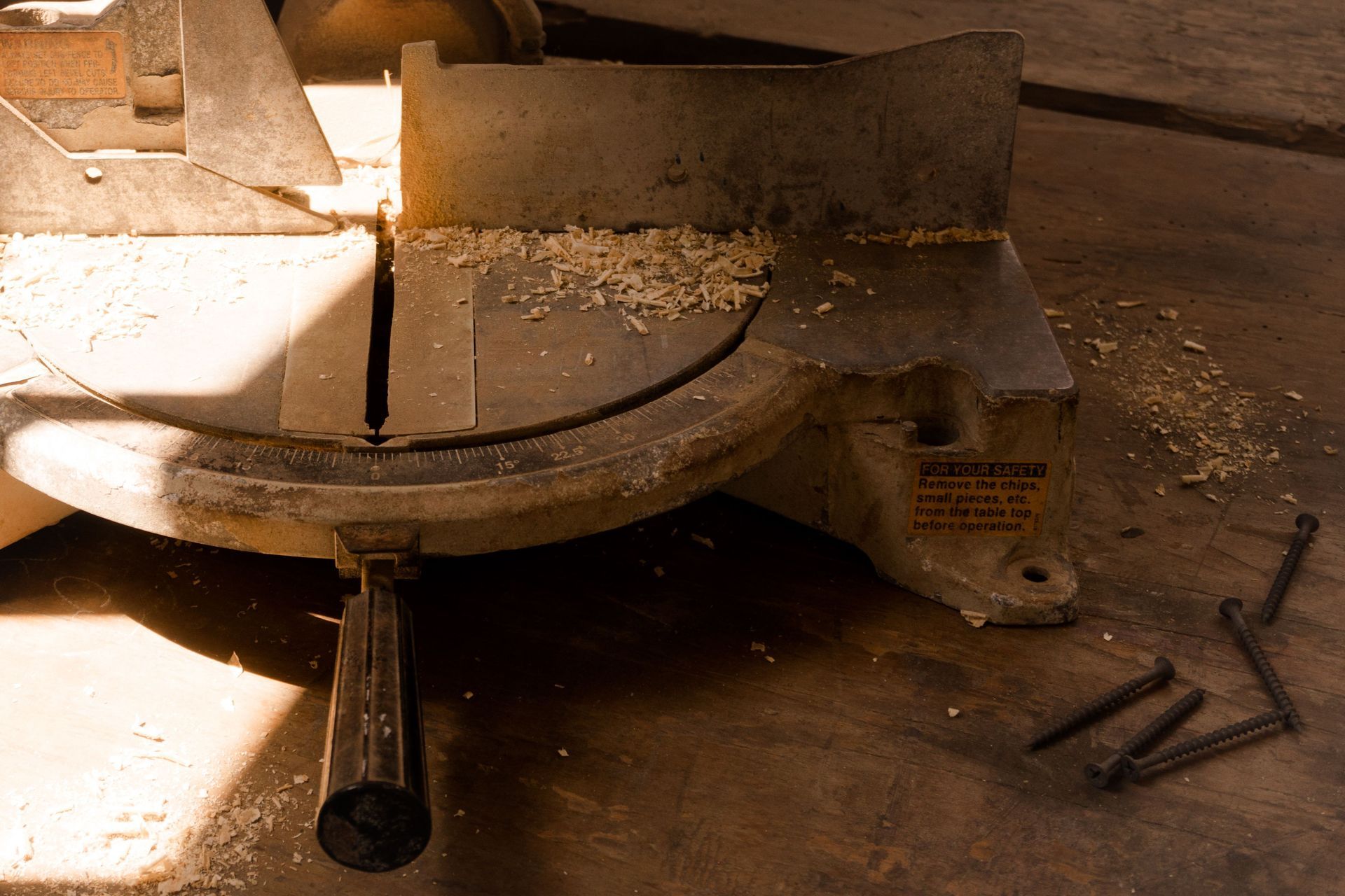 Old metal saw with wood shavings on the floor in a dusty workshop