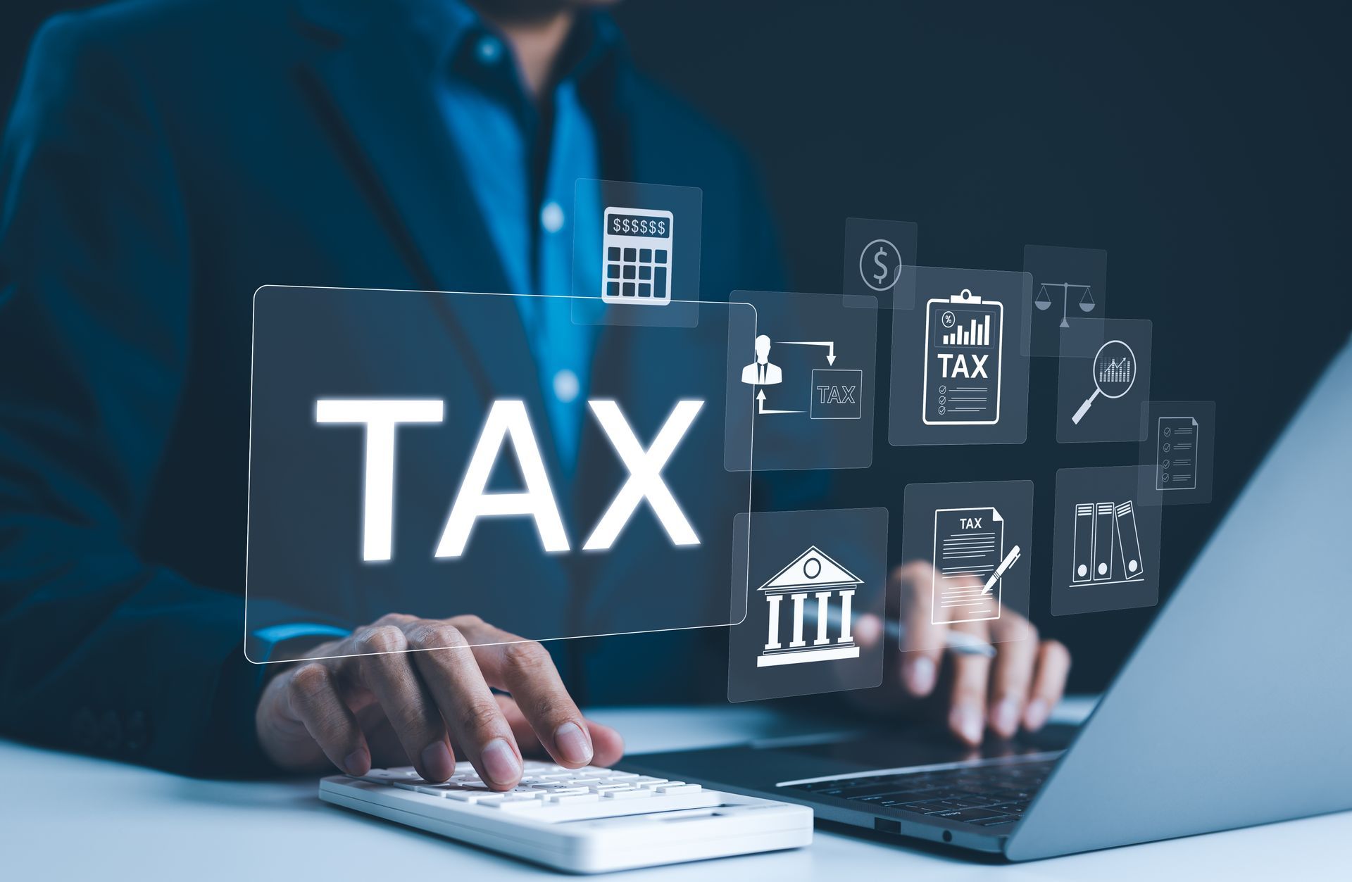 A man is typing on a laptop computer while holding a sign that says tax.