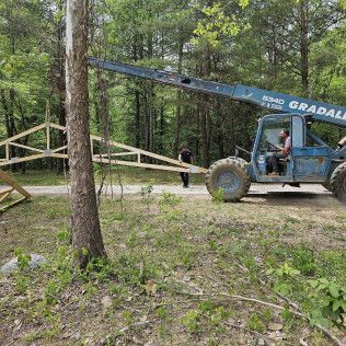 Man Is Driving A Crane Down A Dirt 
Road — Evansville, IN — Red Beaver Construction