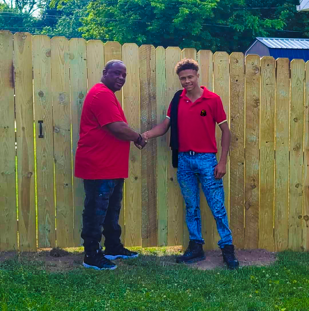 Red Beaver Construction team member standing next to a completed fence project.