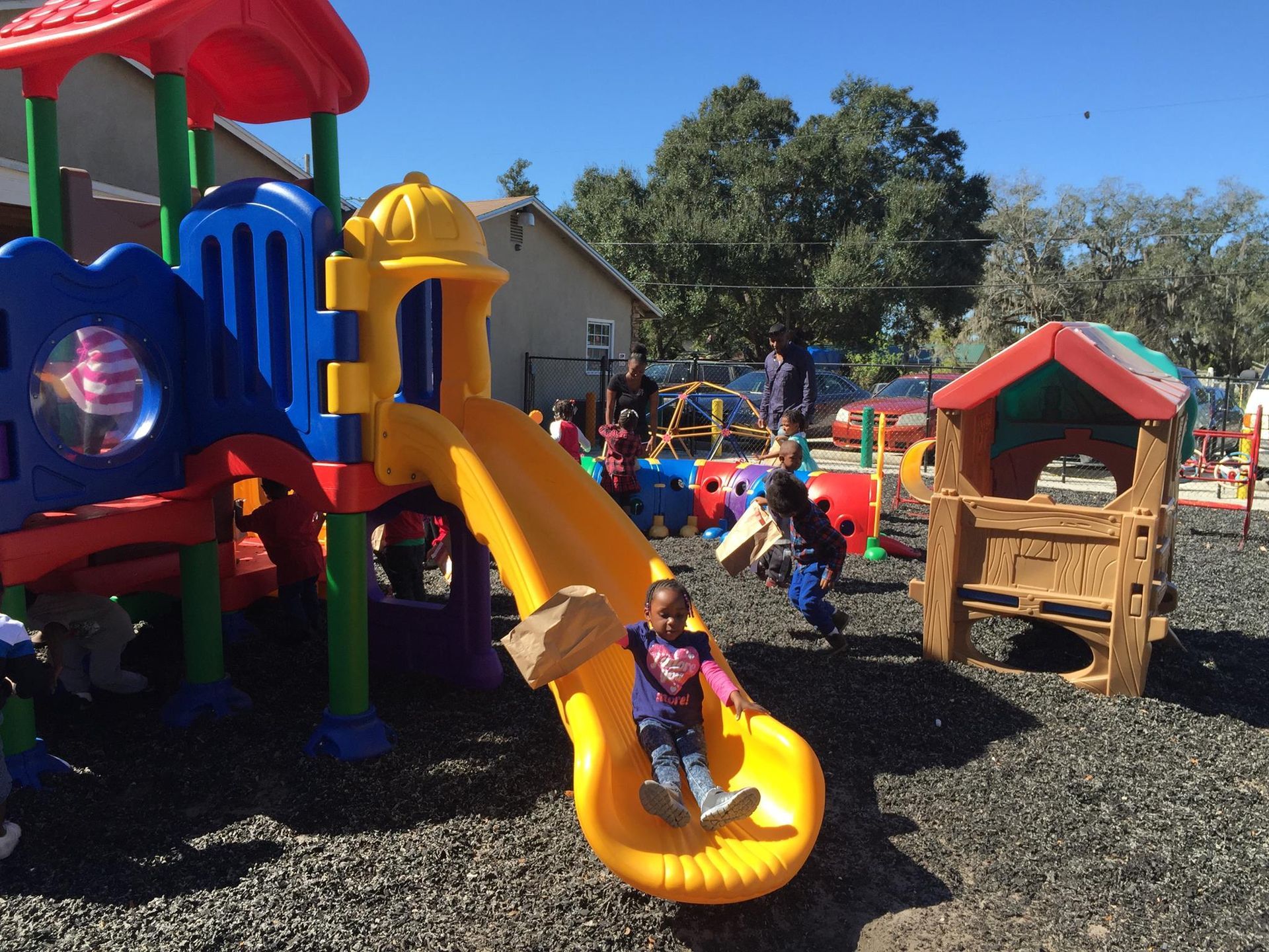 A child is sliding down a yellow slide at a playground