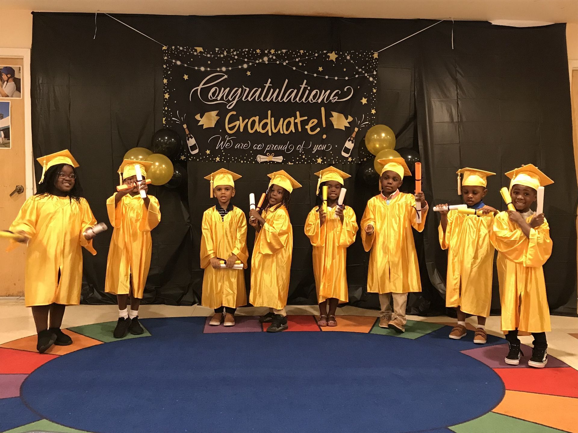 A group of children are standing in front of a sign that says congratulations graduate.