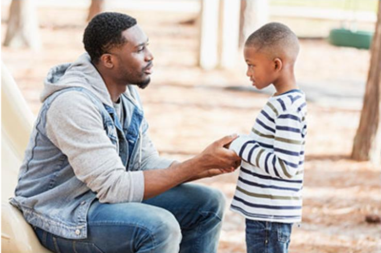 A man is talking to a young boy in a park.