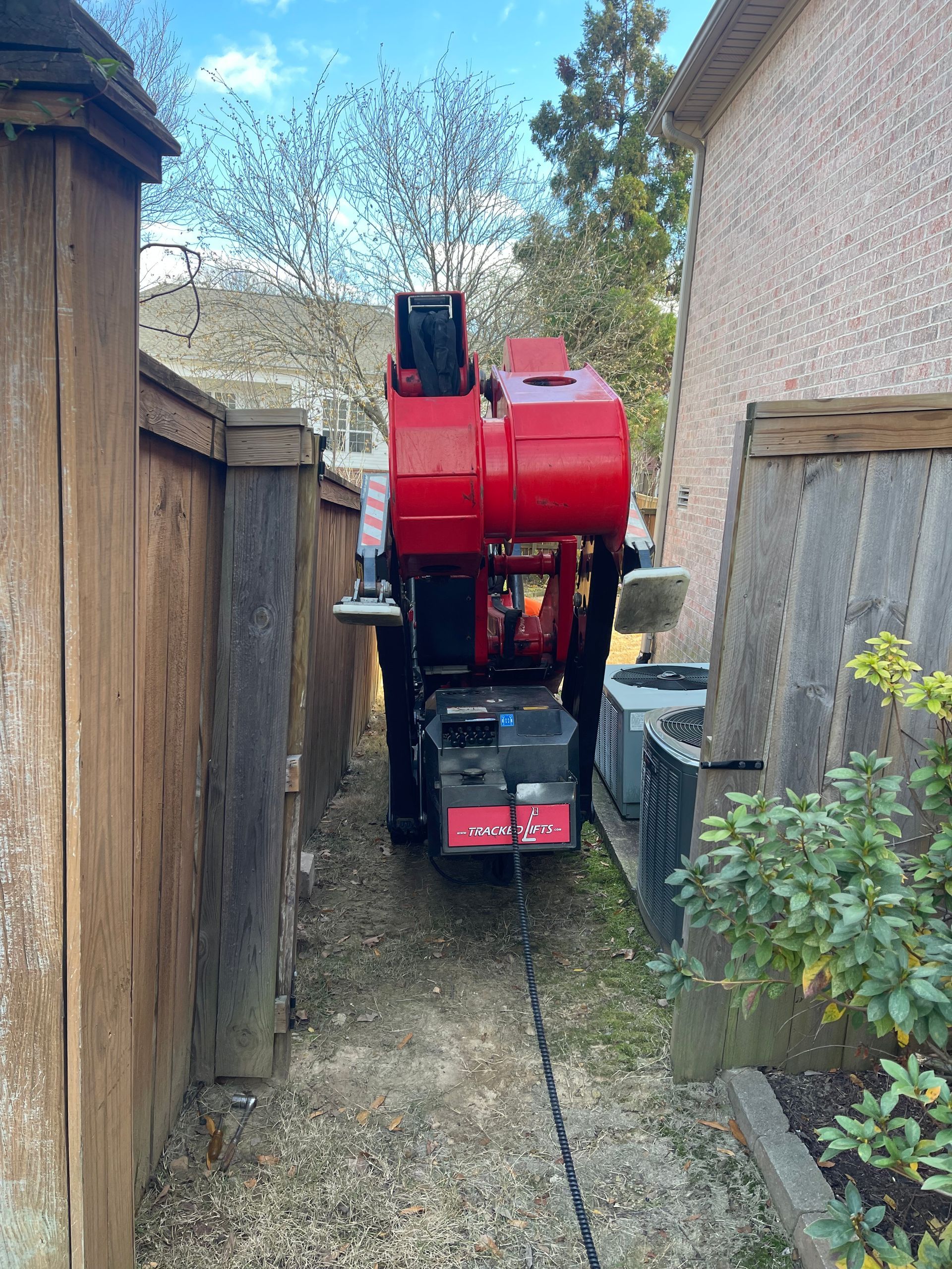 a red truck is parked in a driveway next to a wooden fence .