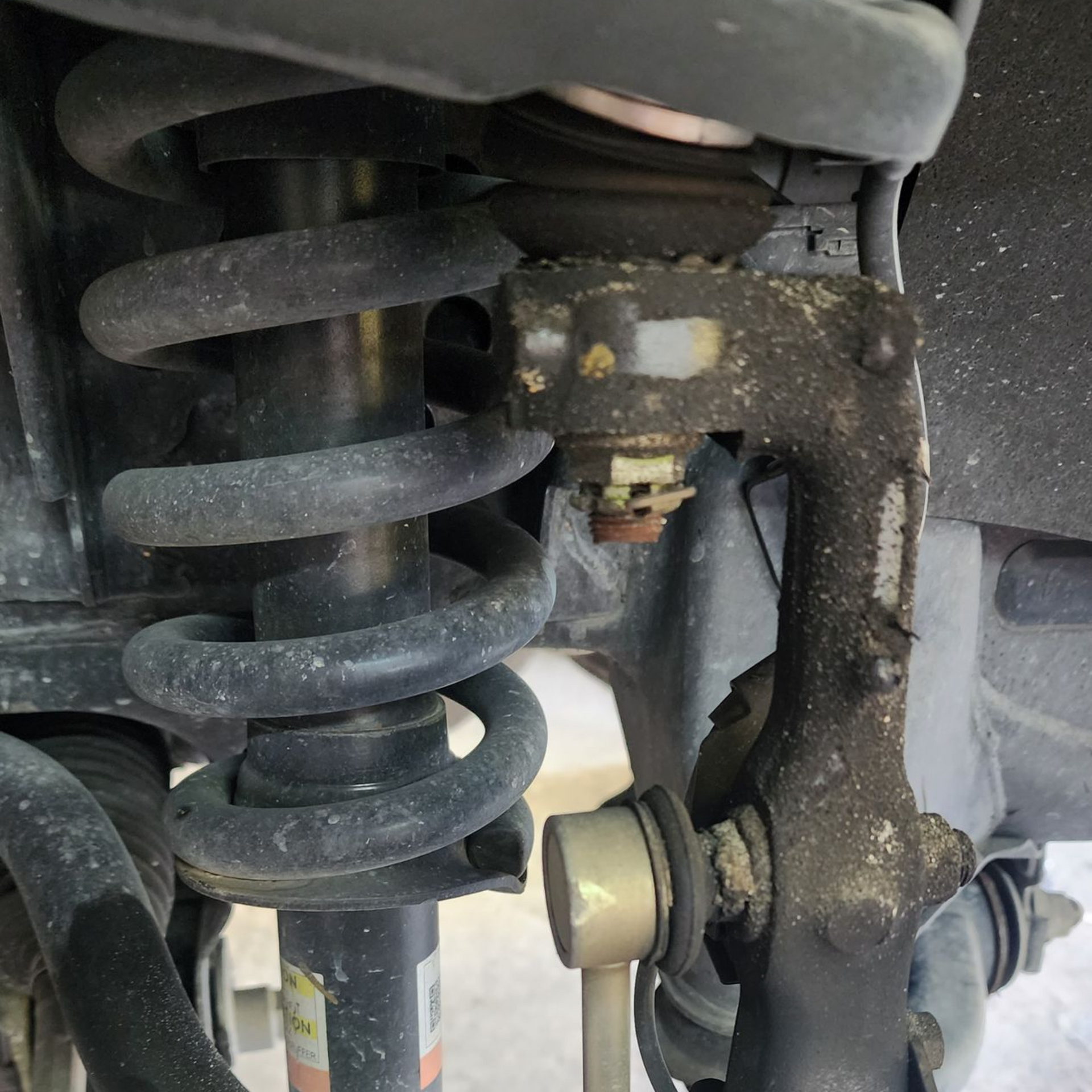 Car suspension system components: spring, shock absorber, ball joint, and sway bar link.