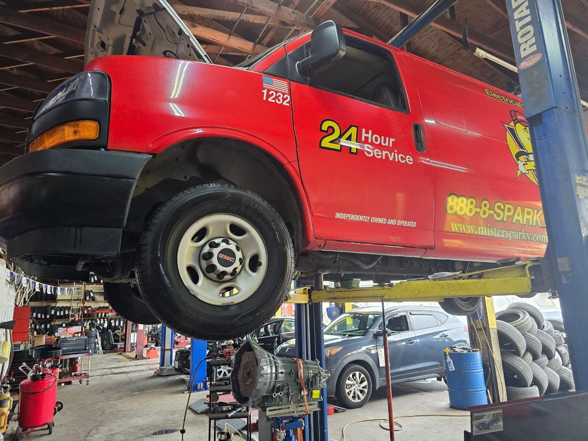 Red service van on a lift inside a repair shop, labeled 
