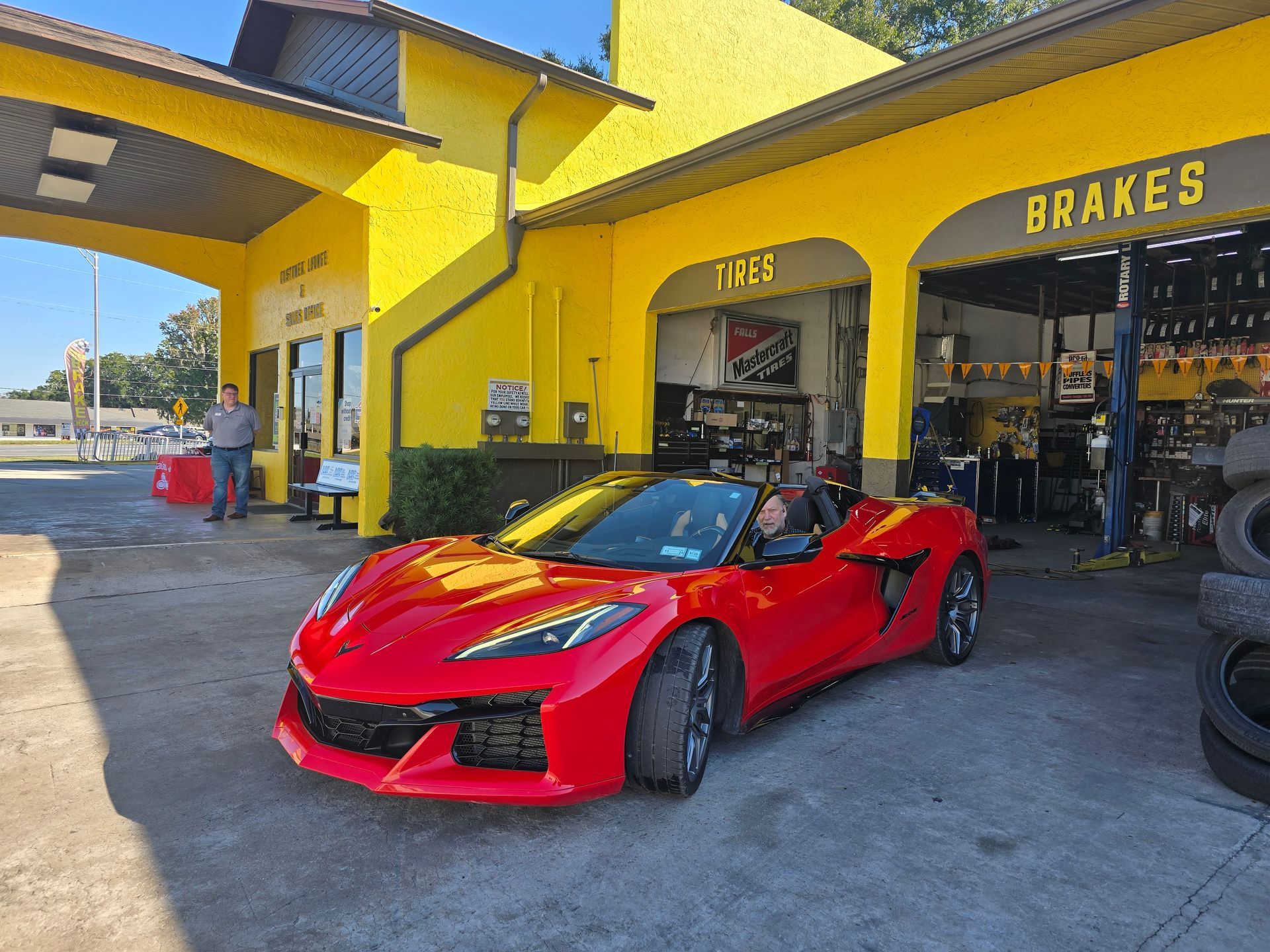 Red Corvette convertible at a yellow auto repair shop with 
