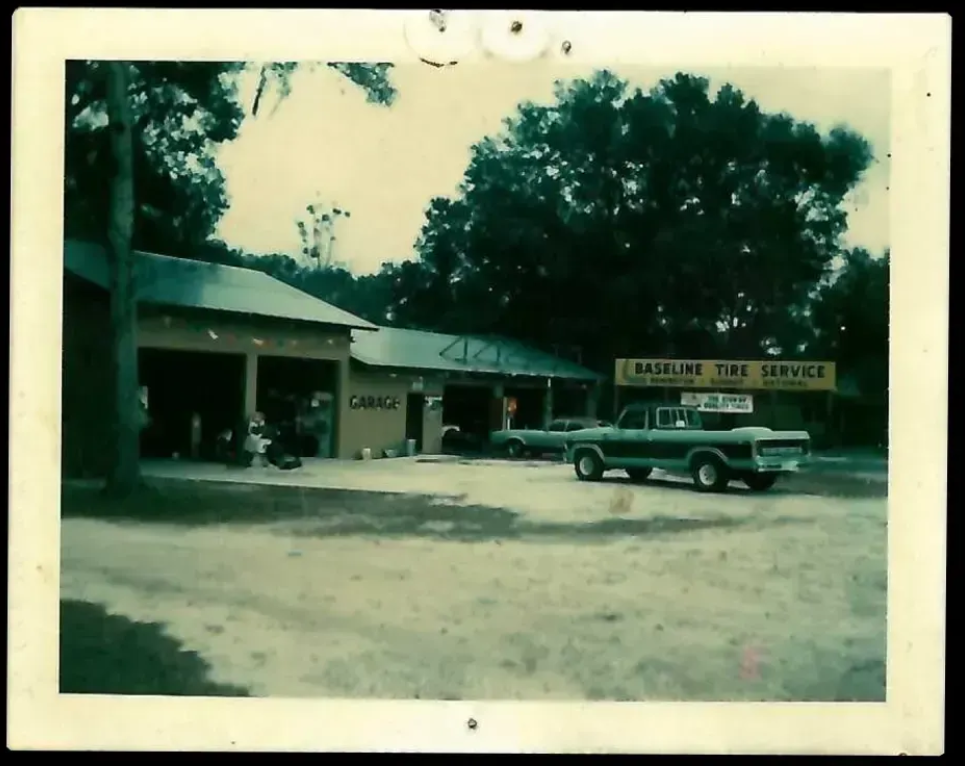Vintage photo of Baseline Tire Service garage with a green pickup truck parked outside.