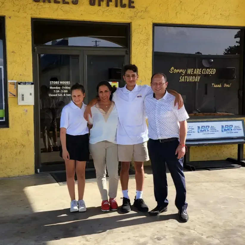 Family of four poses in front of a yellow building with 