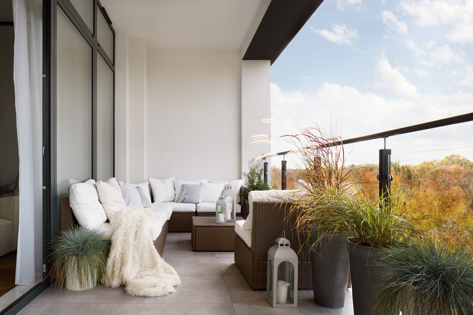 Un balcon avec un canapé, une chaise, une table et des plantes en pot.