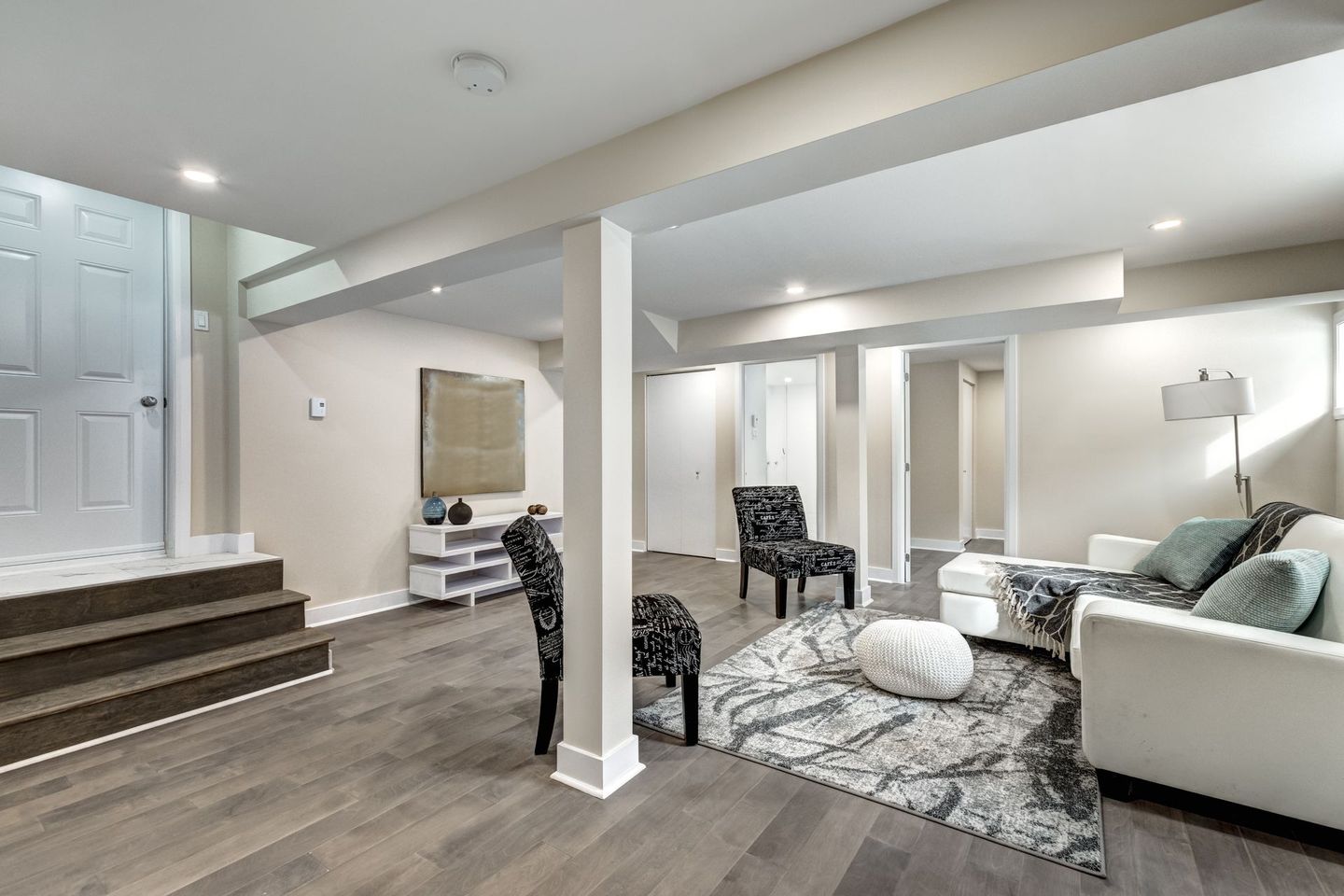 Un salon au sous-sol avec un canapé, des chaises et un tapis.