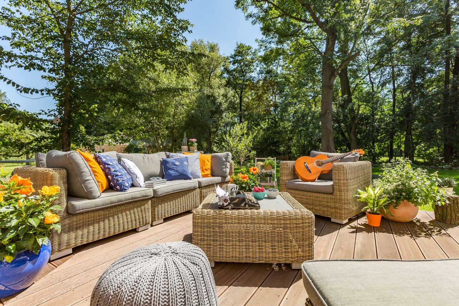 Un patio avec des meubles en osier et une guitare sur la table.
