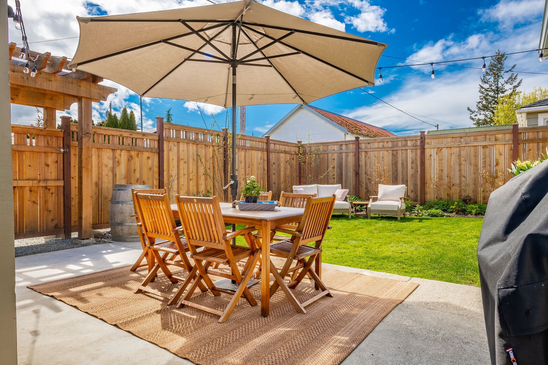 Une cour arrière avec une table et des chaises sous un parasol.