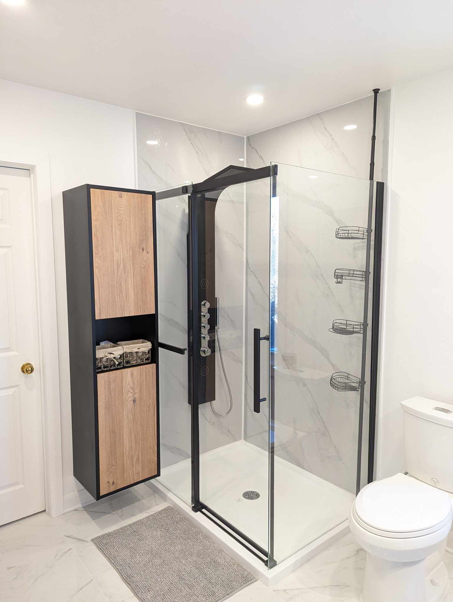 Salle de bains moderne avec douche à l'italienne, baignoire, double vasque et grande fenêtre donnant sur les arbres.