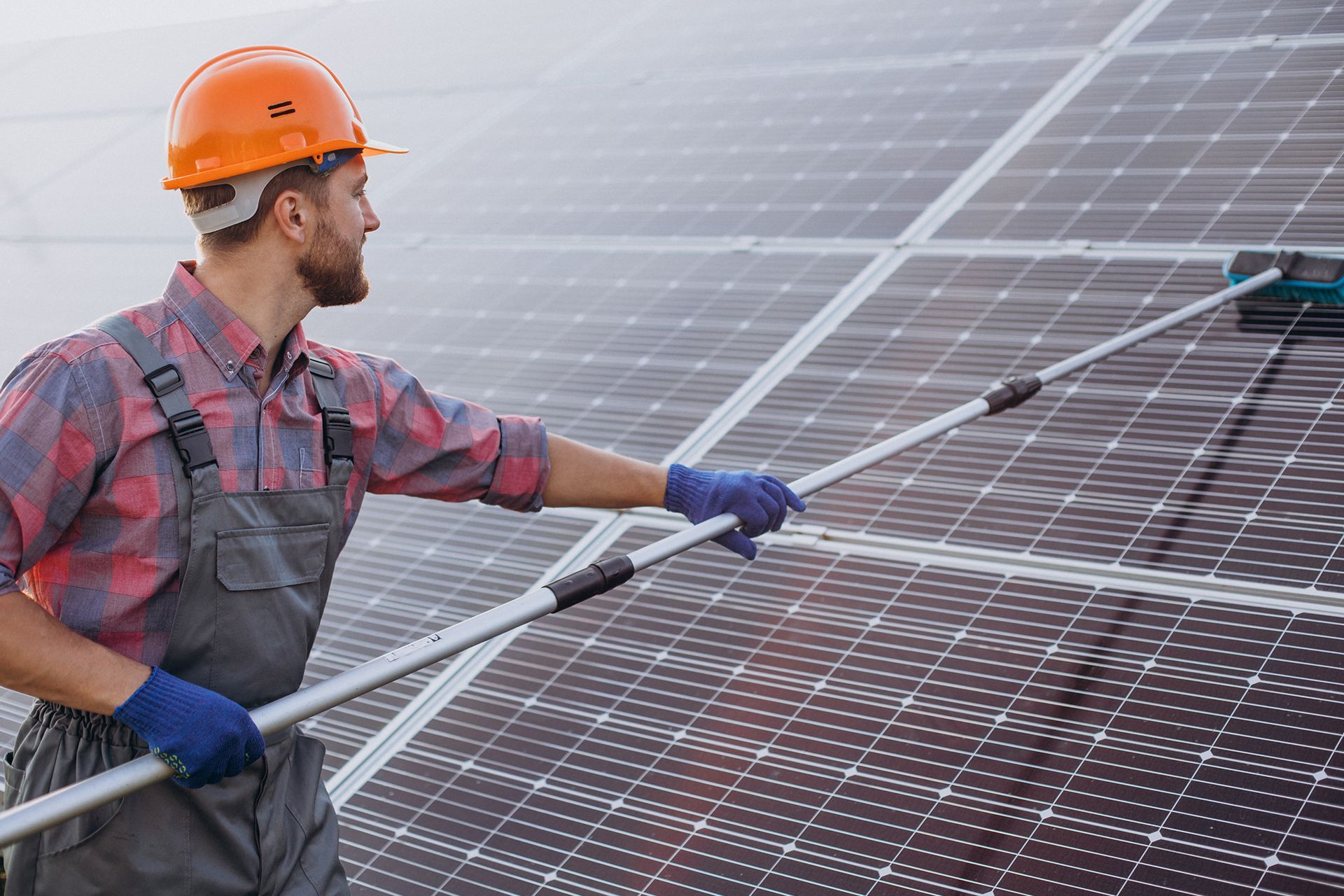 A black cleaning brush attached to a hose on a solar panel on a rooftop.
