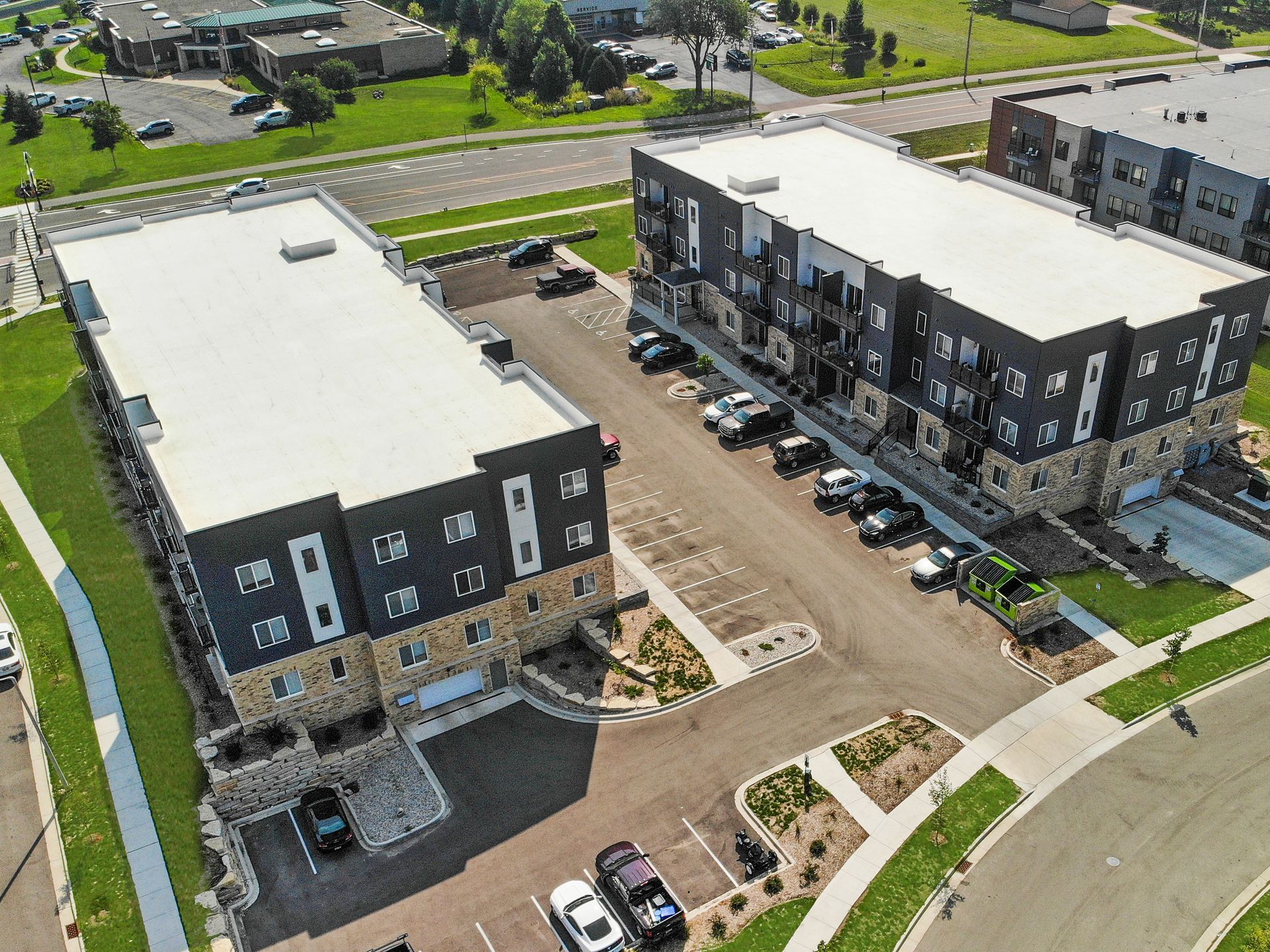 An aerial view of two apartment buildings with cars parked in front of them.