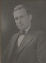 Black-and-white portrait of a man in a suit and bow tie, posed against a plain studio background.