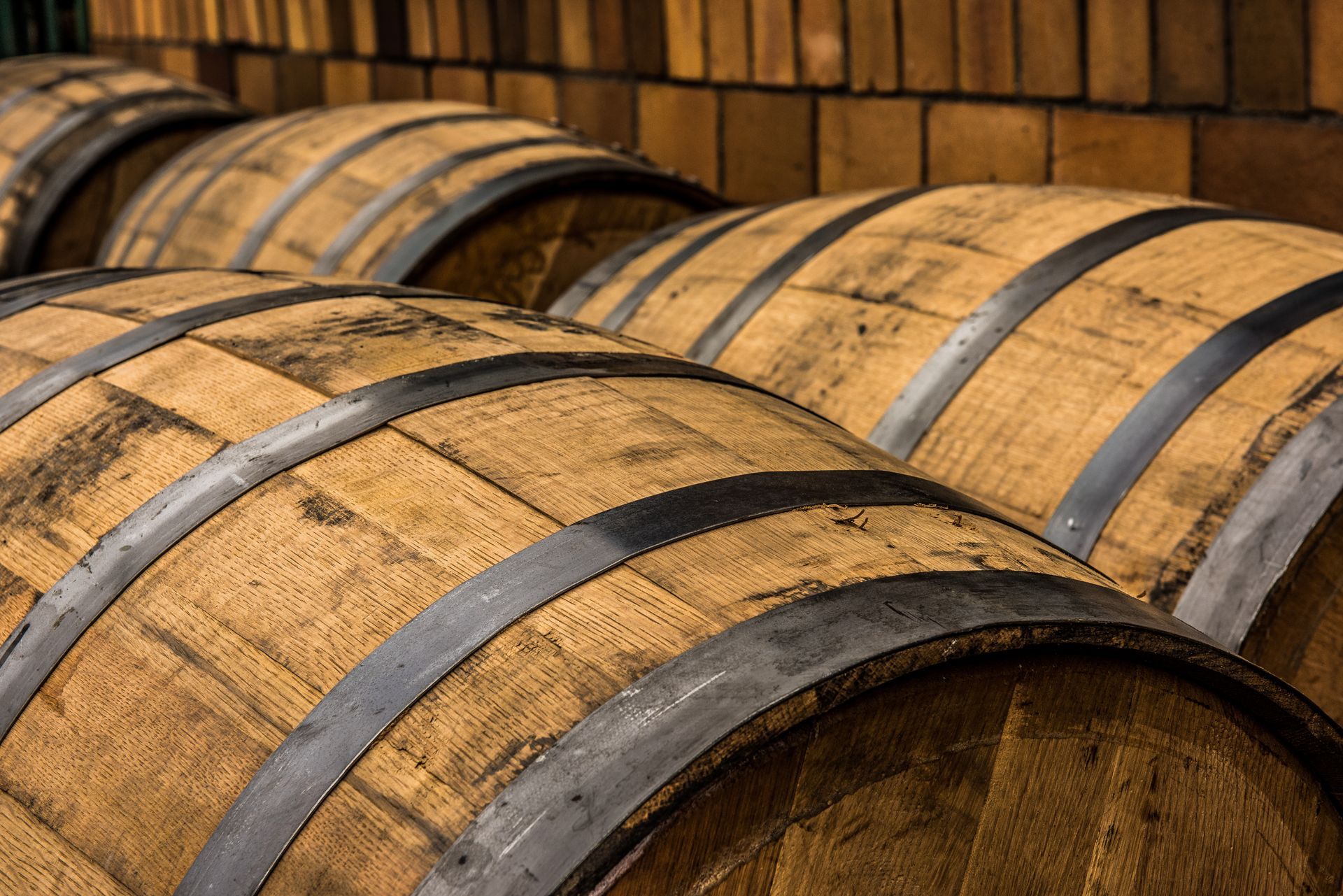 Stacked wooden barrels with dark metal bands in a rustic cellar