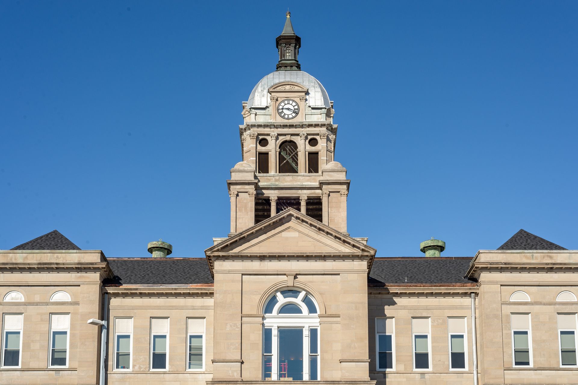 Historic stone building with a clock tower against a clear blue sky
