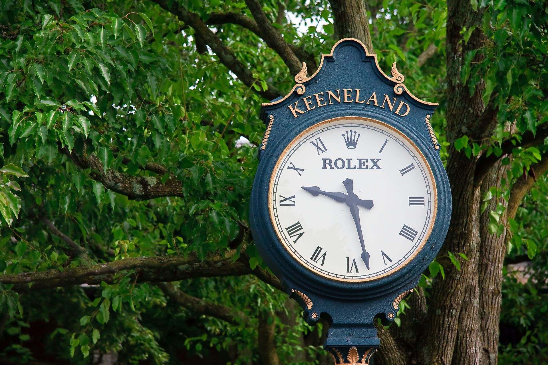 Keeneland Rolex clock on a green tree-lined street