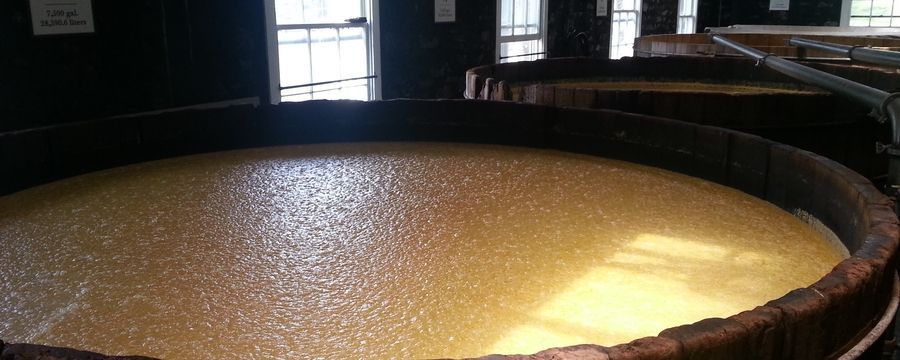 Large round metal vat filled with pale liquid in a dim industrial room