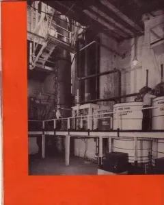 Black-and-white industrial interior with pipes, tanks, and machinery framed by a bright red border.
