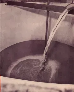 Water pouring from a spout into a basin, creating ripples and foam