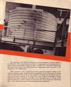 Black-and-white photo of a large cylindrical steel structure in an industrial interior with caption text below