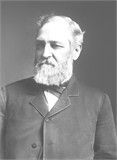 Black-and-white portrait of a bearded man in a suit, facing slightly left.