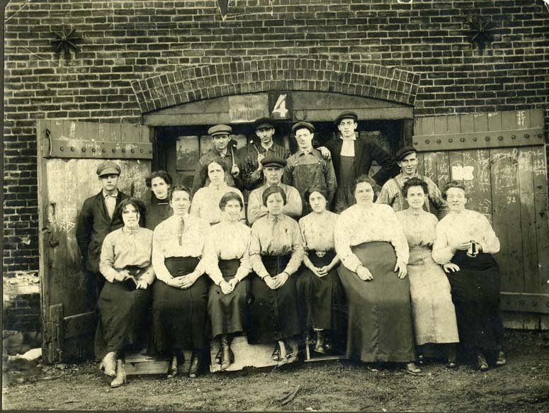 Group of workers posing outside a brick building entrance marked “4”