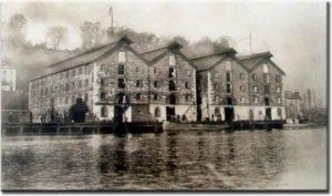 Sepia-toned historic waterfront warehouse complex with reflections on calm water