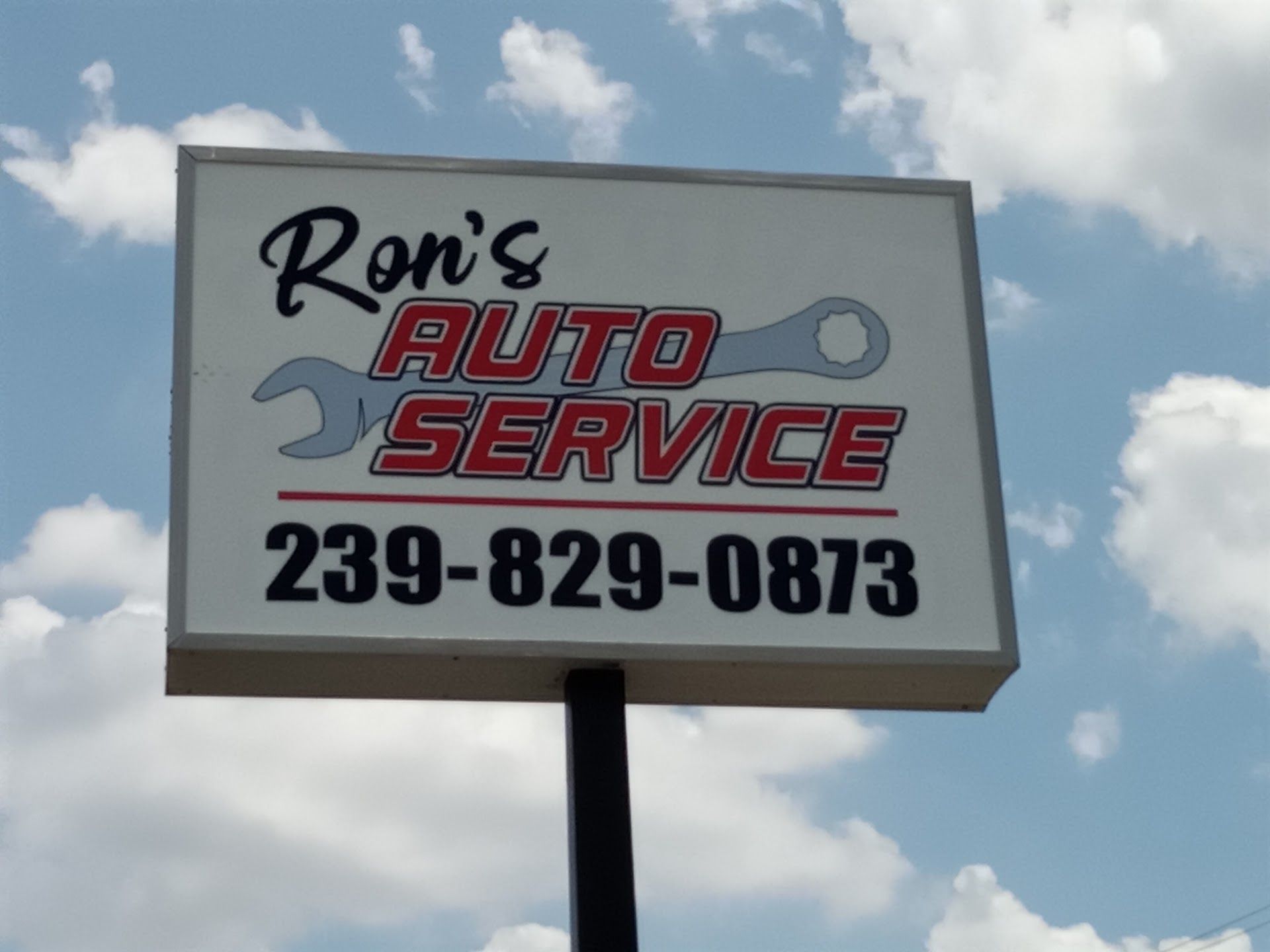 Ron’s Auto Service sign with wrench logo and phone number 239-829-0873 against a cloudy sky | Ron's Auto Service