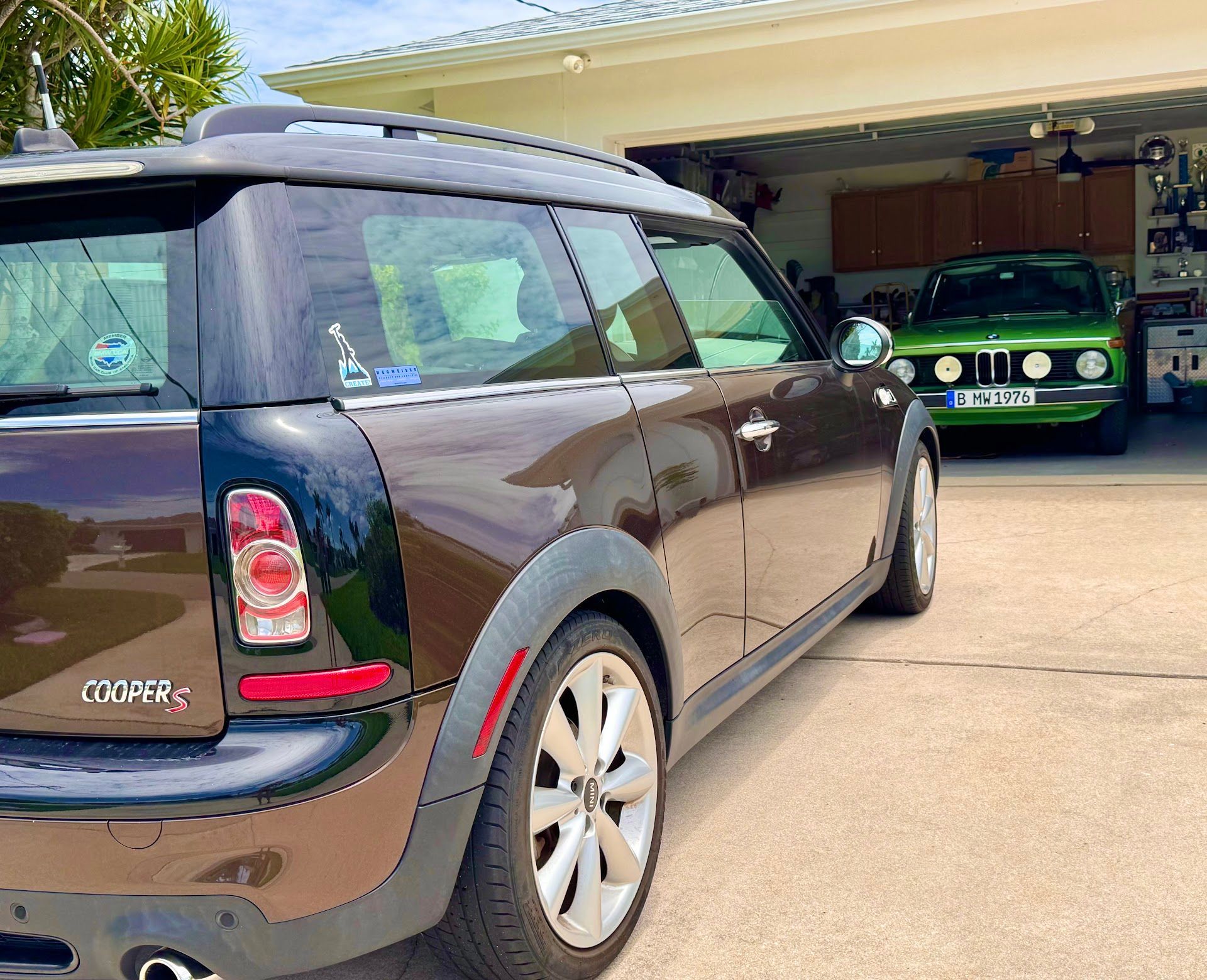 Black Mini Cooper SUV parked in a driveway, with a green car visible inside the garage. | Ron's Auto Service