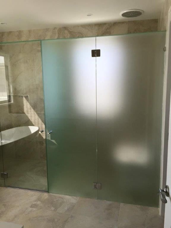 A Bathroom With a Bathtub and a Glass Shower Door — Frameless Shower Installations In Maroochydore, QLD