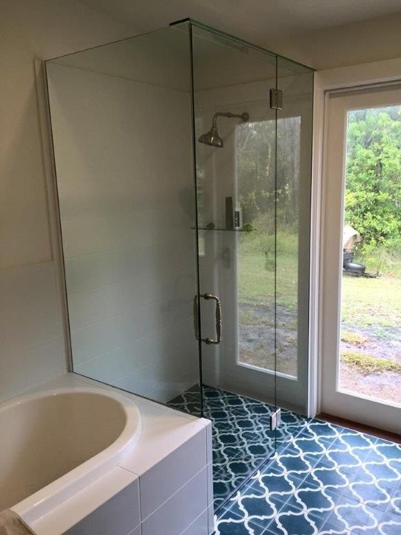 A Bathroom With a Bathtub and a Shower With a Glass Door — Frameless Shower Installations In Maroochydore, QLD