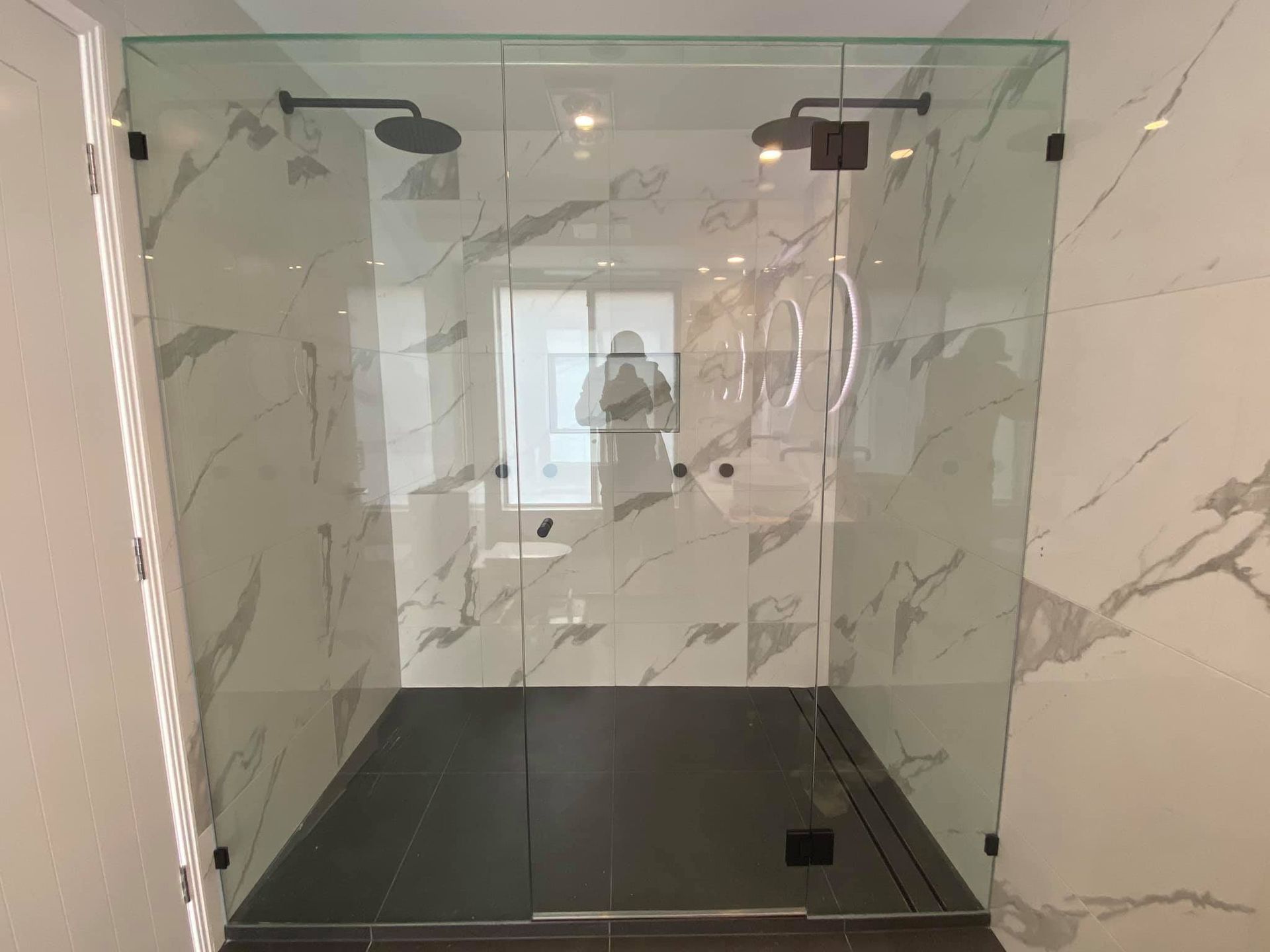A Bathroom With a Walk in Shower and Marble Walls — Frameless Shower Installations in Maroochydore, QLD 