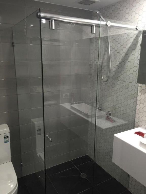 A Bathroom With a Toilet , Sink and Shower Stall — Frameless Shower Installations In Maroochydore, QLD