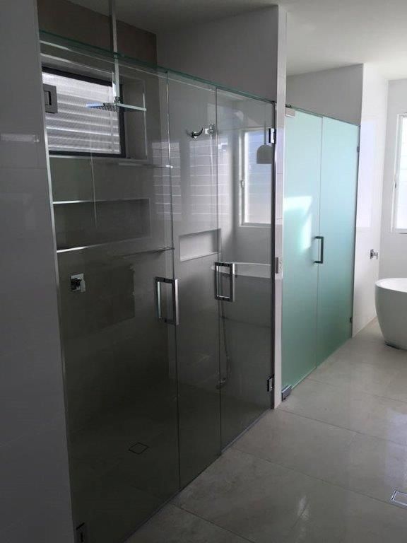 A Bathroom With a Glass Shower Door and a Bathtub — Frameless Shower Installations In Maroochydore, QLD